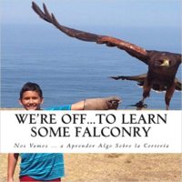 A boy standing on the beach next to an eagle.