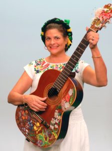 A woman in a white dress holding a guitar